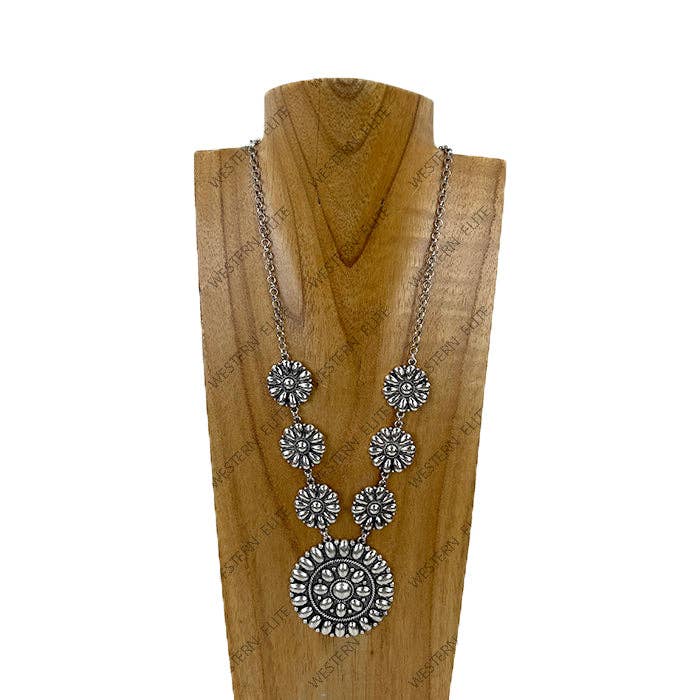 Silver necklace with floral designs on a wooden stand against a white background