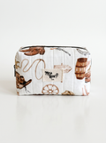 A white quilted cosmetic pouch with a western-themed print featuring brown cowboy boots, a lasso, a wagon wheel, a wooden barrel, and a central patch that reads 'Mesa Rose Co'.