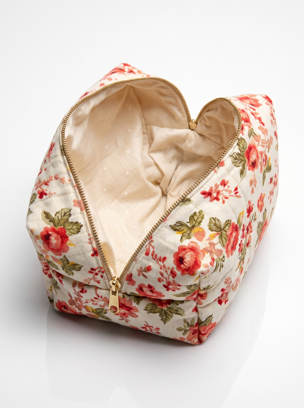 A heart-shaped quilted cosmetic pouch with a red and green floral print, shown open to reveal a beige interior, set against a clean white background.
