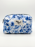 A blue and white floral print cosmetic pouch with a black zipper and a central woven label reading 'MESA ROSE CO'.
